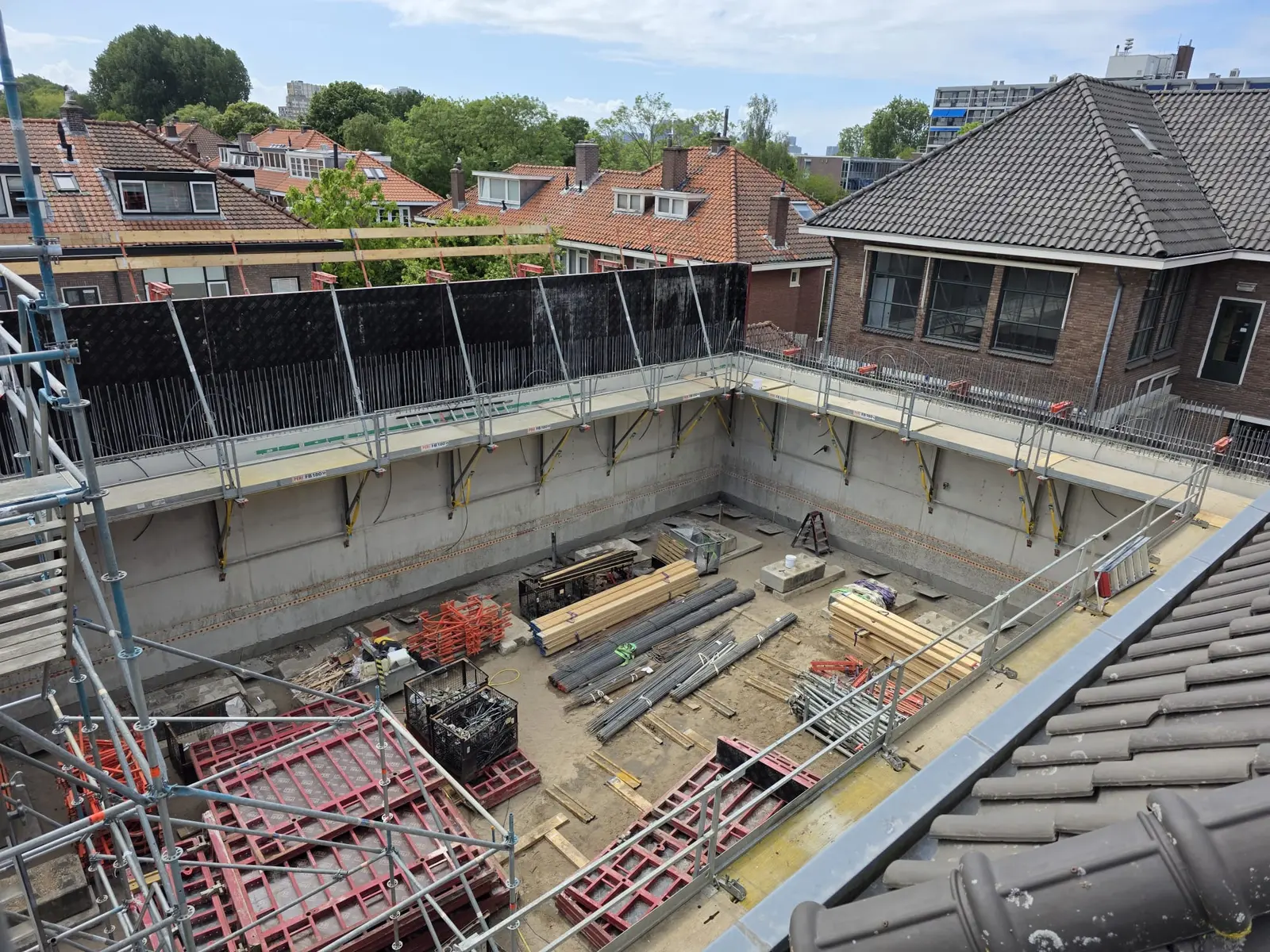 Bekiste bouwkuip met betonwanden en bekistingsmateriaal op de bouwplaats, klaar voor de stort