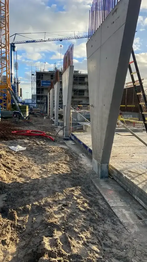 Geplaatste prefab betonnen kolommen en wandelementen op de bouwplaats met torenkraan