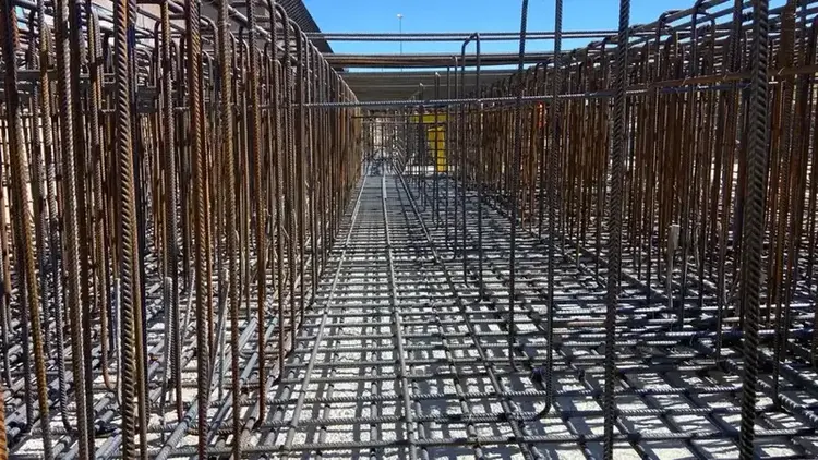 Wapeningskorven in lange rij op funderingsplaat, perspectief tussen betonstaal door