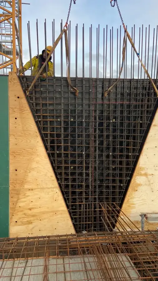 V-vormige wapening in bekisting met vlechter op steiger voor kelderwand